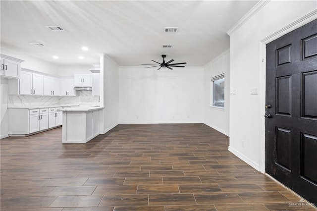 kitchen featuring backsplash, ceiling fan, crown molding, and white cabinets