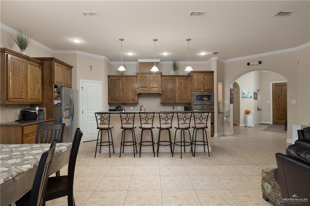 kitchen with light tile patterned flooring, a breakfast bar area, tasteful backsplash, decorative light fixtures, and appliances with stainless steel finishes