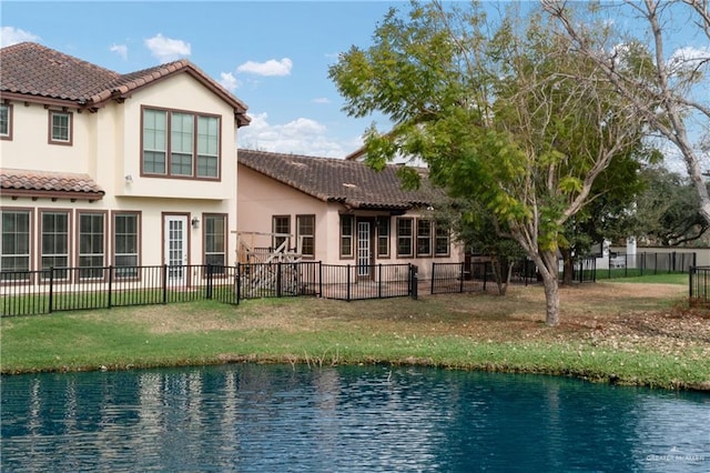 back of property with a water view and a yard