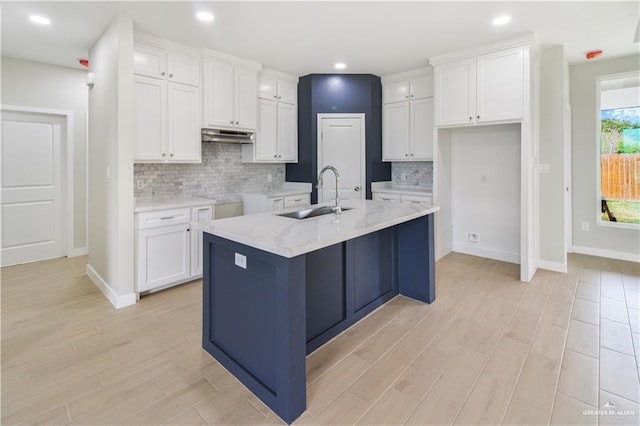 kitchen with light wood-type flooring, a kitchen island with sink, white cabinets, and a sink