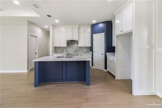 kitchen with backsplash, a sink, visible vents, and white cabinets