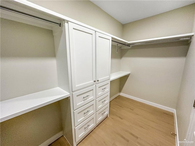 walk in closet with light wood-type flooring and built in study area