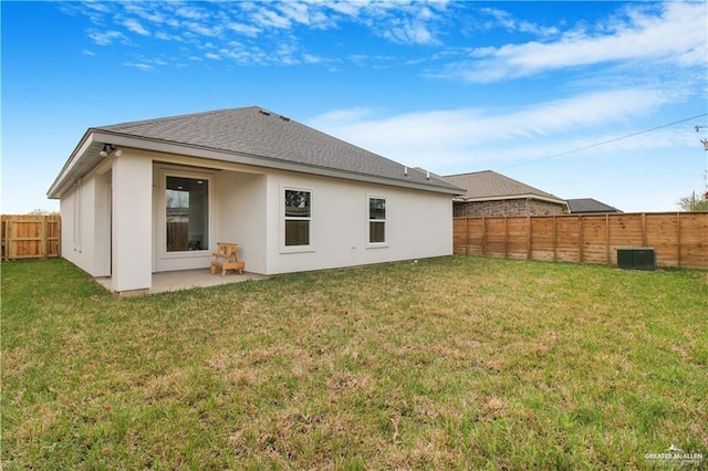 rear view of house featuring a shingled roof, a fenced backyard, a yard, and stucco siding