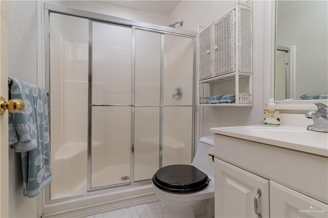 bathroom featuring tile patterned flooring, toilet, vanity, and walk in shower