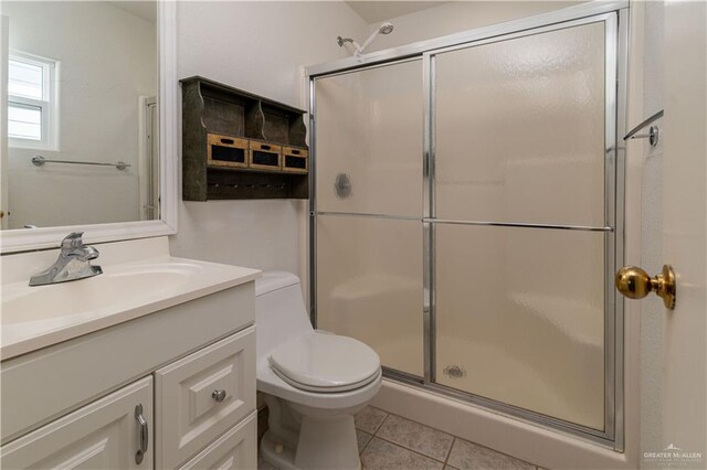 bathroom with tile patterned floors, vanity, an enclosed shower, and toilet