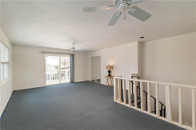 unfurnished room with dark carpet and ceiling fan