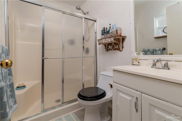 bathroom featuring vanity, toilet, and a shower with shower door