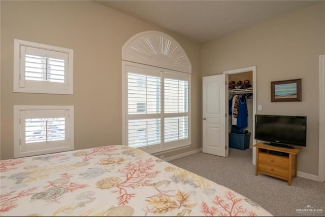 carpeted bedroom featuring a walk in closet and a closet