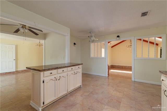 kitchen featuring ceiling fan, white cabinets, and dark stone counters