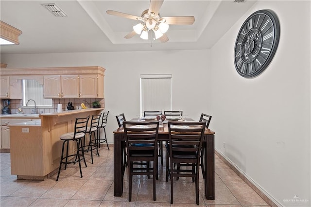 dining area featuring sink, light tile patterned floors, and a raised ceiling