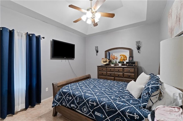 bedroom with ceiling fan, light tile patterned floors, and a raised ceiling