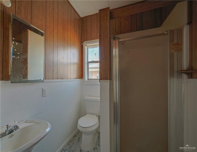 bathroom with toilet, a shower with door, wooden walls, and sink