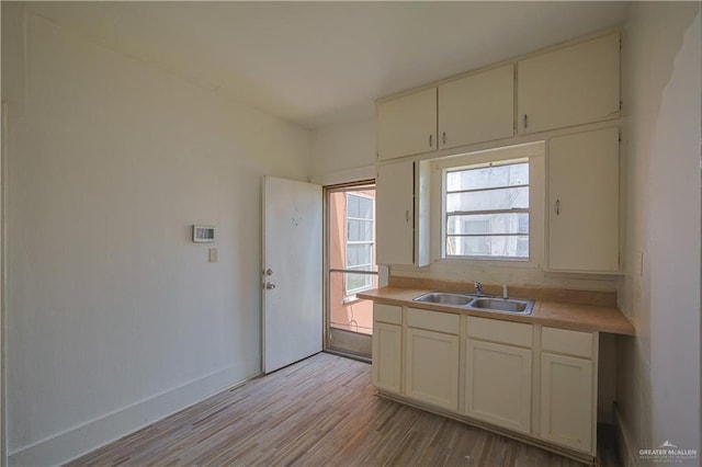 kitchen with white cabinets, light hardwood / wood-style floors, and sink