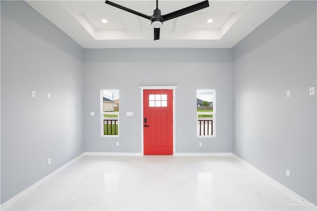 foyer entrance with ceiling fan, a healthy amount of sunlight, and coffered ceiling