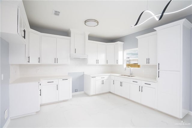 kitchen featuring white cabinets, backsplash, and sink