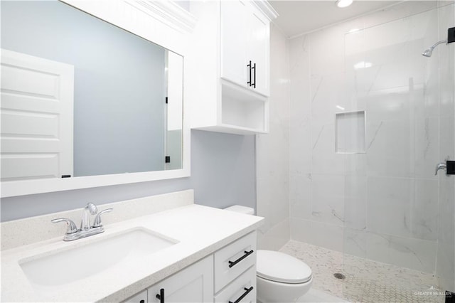 bathroom featuring toilet, a tile shower, and vanity