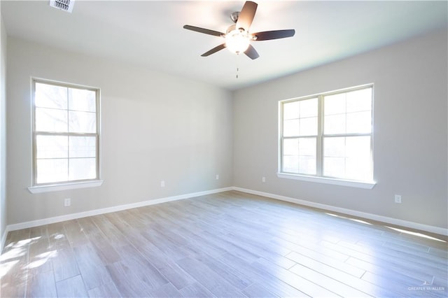 empty room featuring ceiling fan, light hardwood / wood-style flooring, and a healthy amount of sunlight