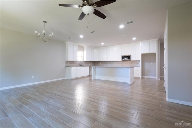 unfurnished living room featuring light hardwood / wood-style floors and ceiling fan with notable chandelier