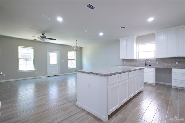 kitchen featuring white cabinets, a center island, tasteful backsplash, and light hardwood / wood-style flooring