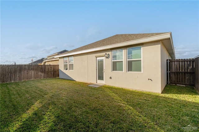 back of house with a lawn, a fenced backyard, and stucco siding