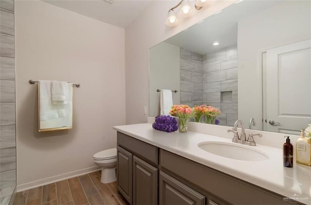 bathroom with baseboards, toilet, wood tiled floor, a tile shower, and vanity