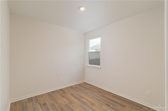 spare room with recessed lighting, wood finished floors, and baseboards