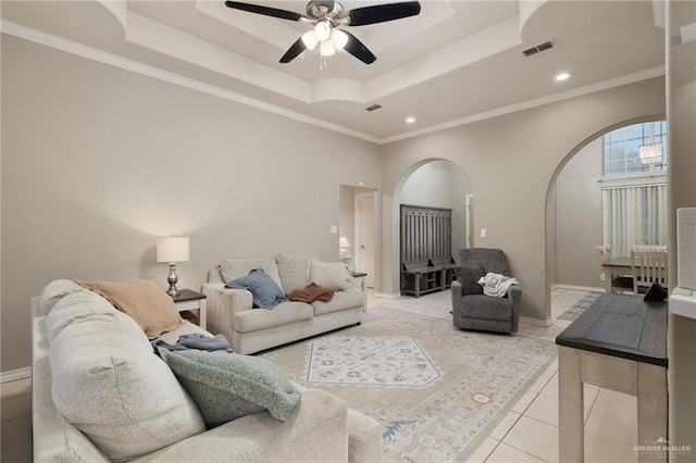 tiled living room with ornamental molding, ceiling fan, and a tray ceiling