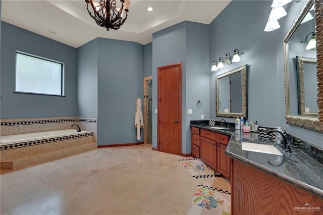 bathroom with a notable chandelier, vanity, tiled bath, and a tray ceiling