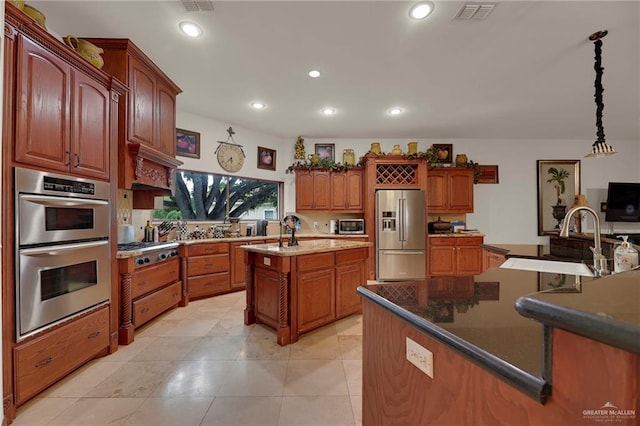 kitchen featuring stainless steel appliances, sink, pendant lighting, a center island with sink, and dark stone countertops