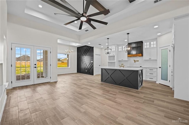 kitchen featuring open floor plan, white cabinetry, light countertops, and a tray ceiling