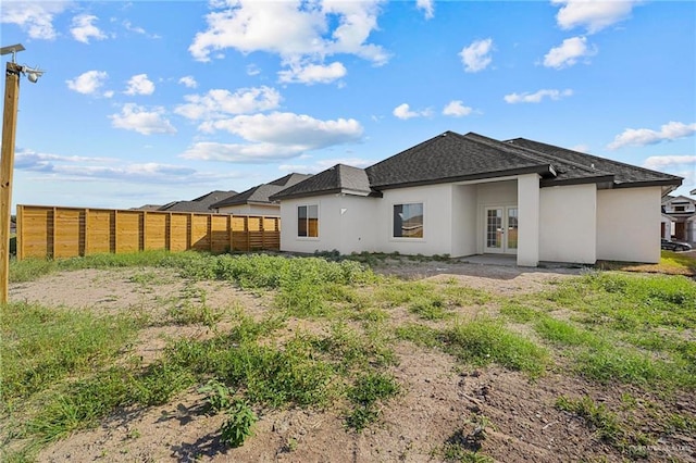 back of property featuring stucco siding, fence, and french doors