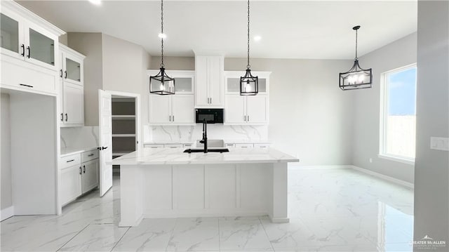 kitchen with backsplash, a kitchen island with sink, white cabinets, and hanging light fixtures