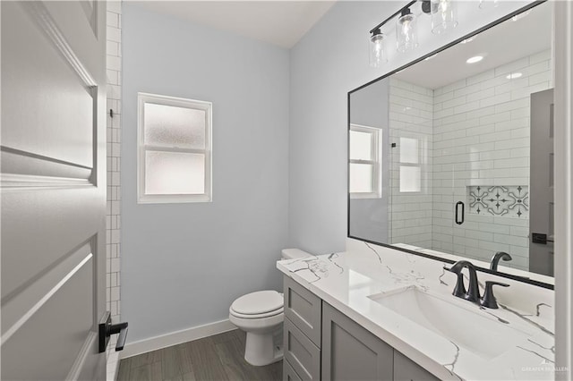 bathroom with hardwood / wood-style floors, vanity, toilet, and walk in shower