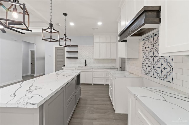 kitchen featuring a center island, white cabinets, decorative light fixtures, and custom exhaust hood