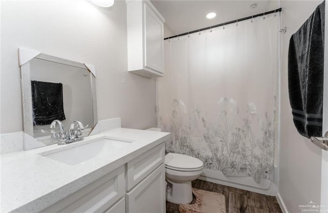 full bathroom featuring hardwood / wood-style floors, vanity, shower / bath combination with curtain, and toilet