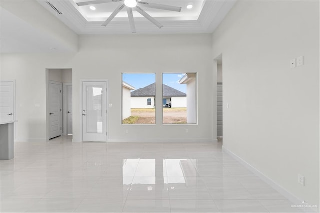 empty room with a tray ceiling, a towering ceiling, and ceiling fan