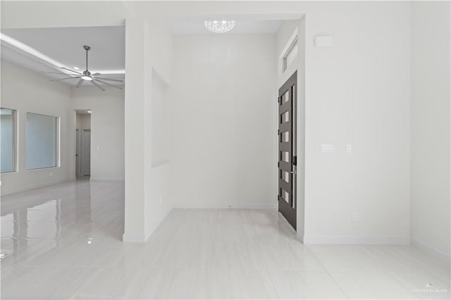 unfurnished room featuring ceiling fan with notable chandelier and a high ceiling