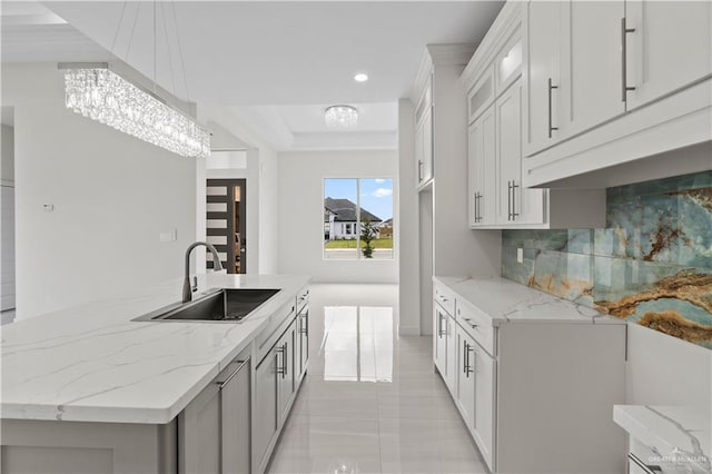 kitchen with sink, pendant lighting, white cabinets, and light stone counters