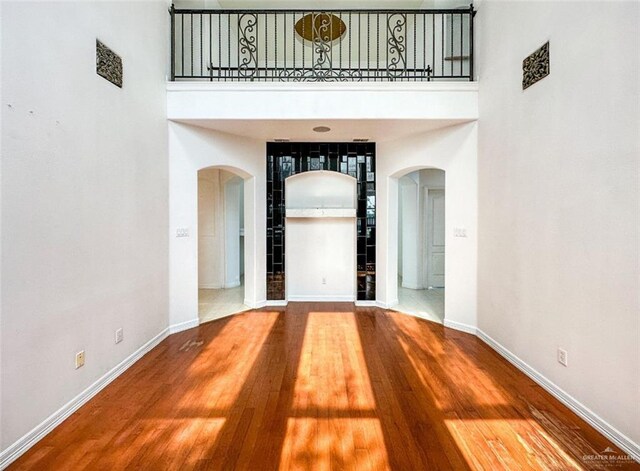 5605 N 41st St, Mcallen, TX 78504 - empty room with arched walkways, baseboards, a towering ceiling, and wood finished floors