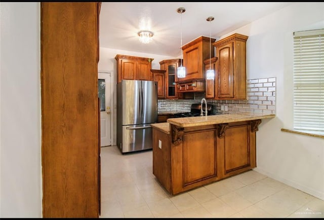 5605 N 41st St, Mcallen, TX 78504 - kitchen featuring freestanding refrigerator, a peninsula, backsplash, glass insert cabinets, and brown cabinetry