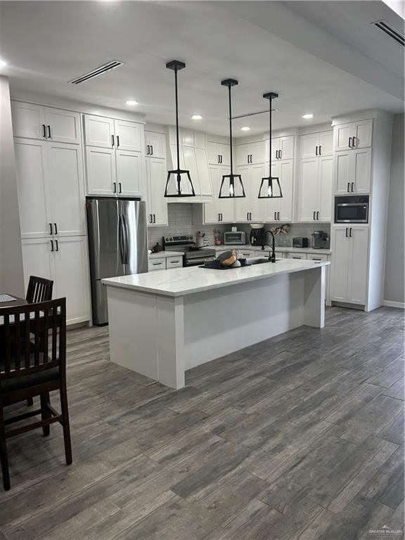 kitchen with an island with sink, decorative light fixtures, stainless steel appliances, and dark hardwood / wood-style floors