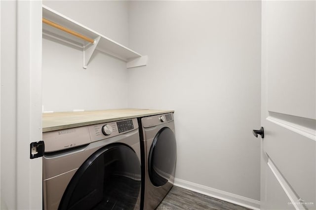 clothes washing area with laundry area, baseboards, washer and clothes dryer, and dark wood-type flooring