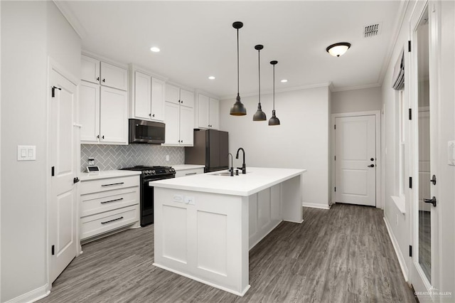 kitchen featuring tasteful backsplash, white cabinets, light countertops, black appliances, and a sink