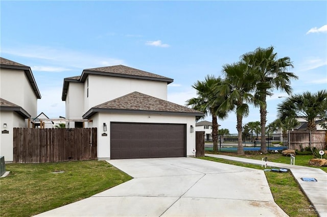 view of front of property with an attached garage, fence, driveway, stucco siding, and a front yard