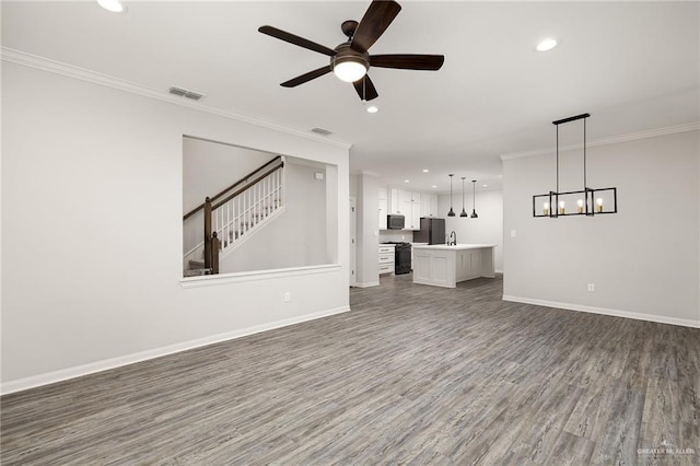 unfurnished living room featuring crown molding, visible vents, stairway, wood finished floors, and baseboards