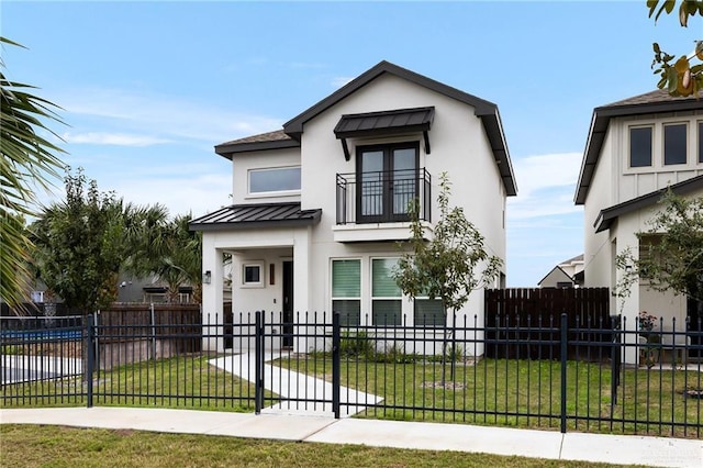 view of front facade with a fenced front yard, metal roof, a standing seam roof, a front yard, and stucco siding