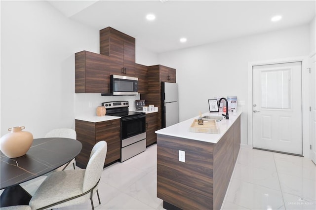 kitchen with a sink, light countertops, appliances with stainless steel finishes, modern cabinets, and marble finish floor