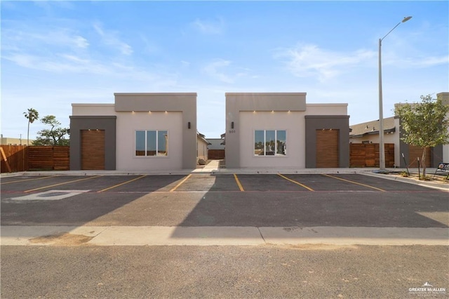 view of property with uncovered parking and fence