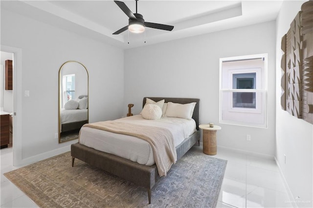 bedroom with a raised ceiling, light tile patterned floors, baseboards, and ceiling fan