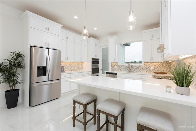 5703 N 44th Ln, Mcallen, TX 78504 - kitchen featuring appliances with stainless steel finishes, a peninsula, light countertops, tasteful backsplash, and a kitchen bar